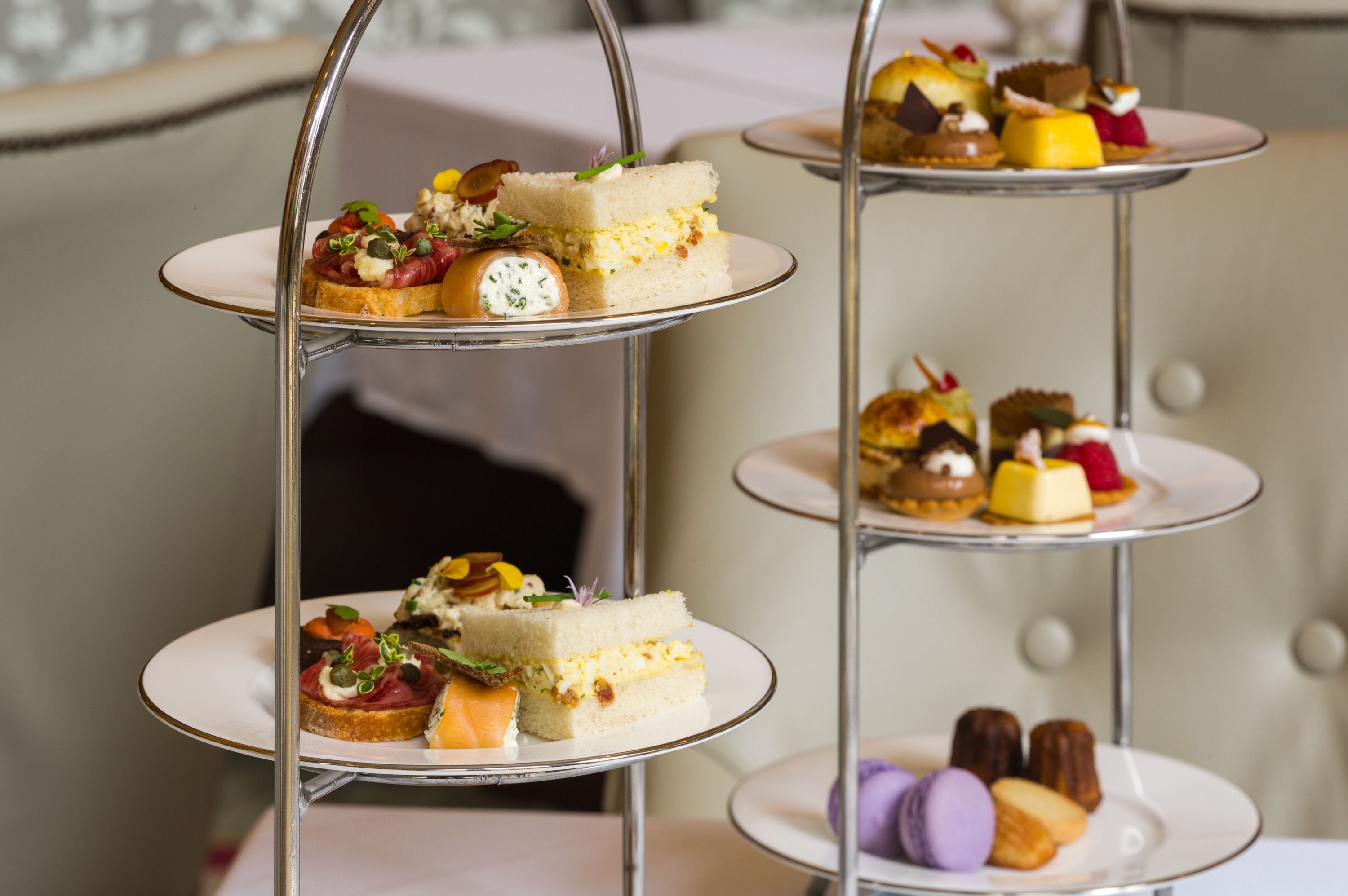 A three-tiered dessert stand with various pastries and sandwiches.