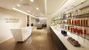 A modern spa and club interior with a reception desk, shelves of products, and a wooden floor.