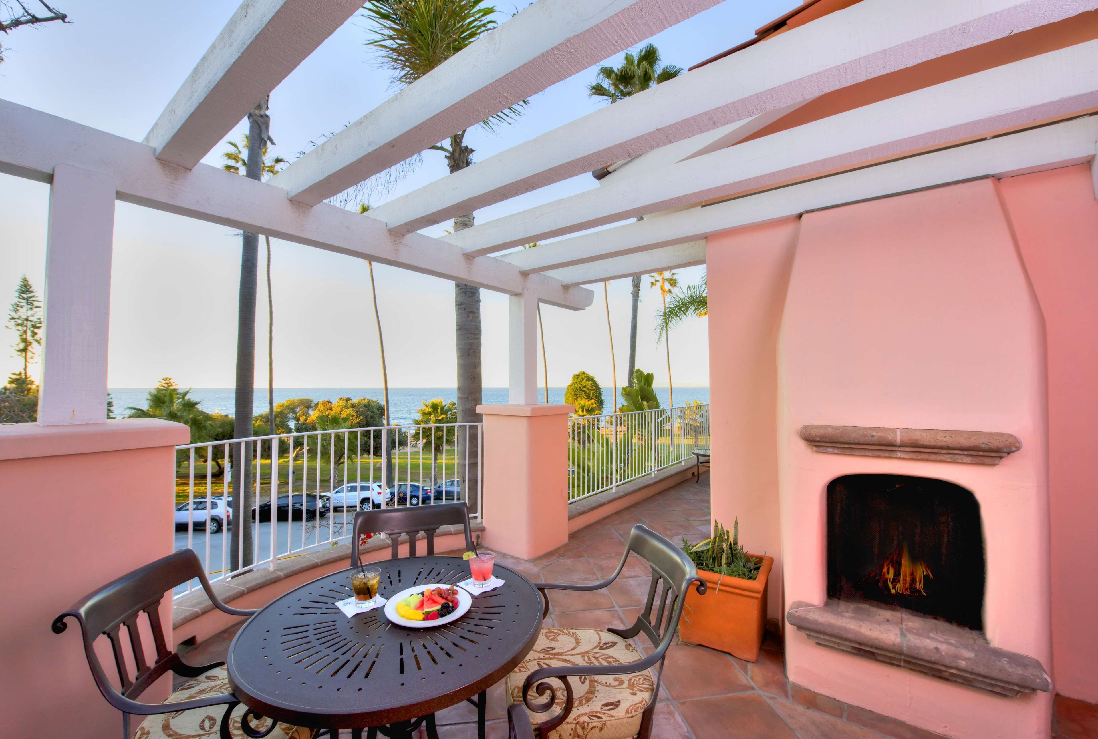A balcony with a table, chairs, a fire pit, and a view of the ocean.