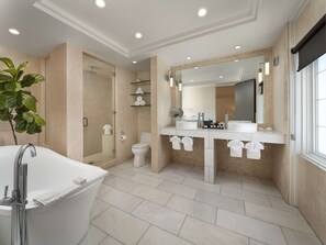 A modern bathroom with a bathtub, two sinks, a toilet, and a shower.