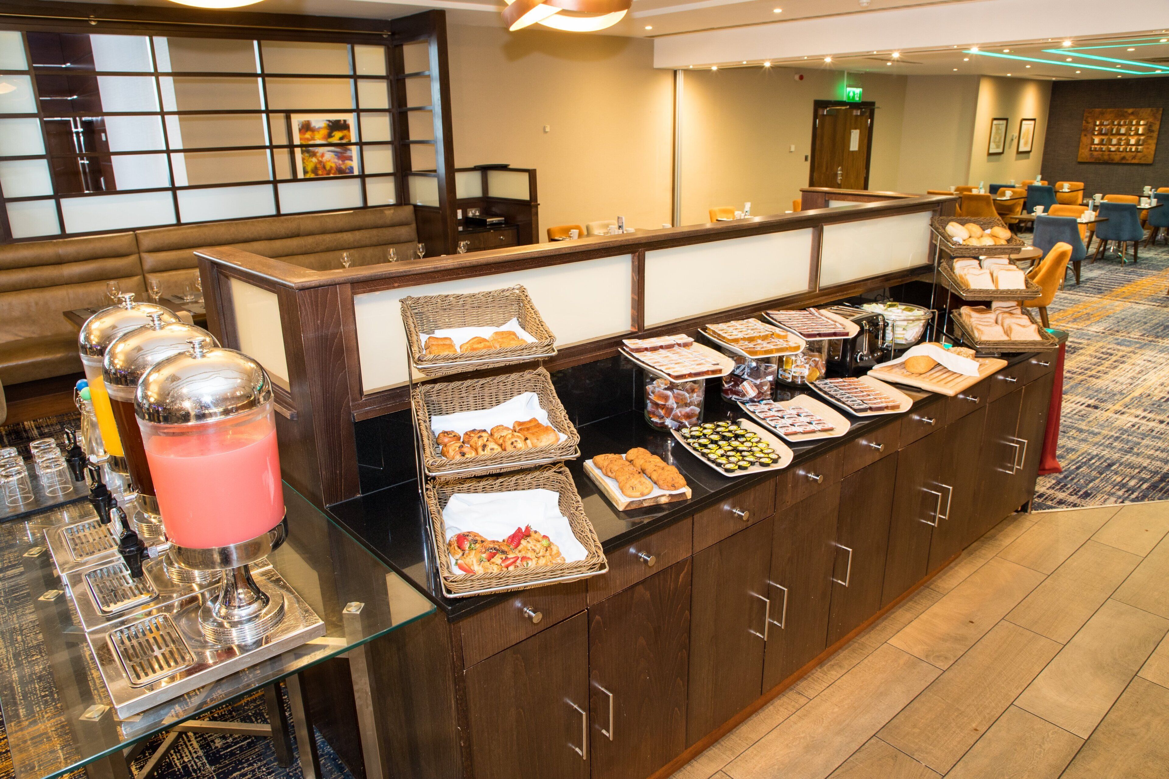 A buffet setup with various food items and a pink beverage dispenser.