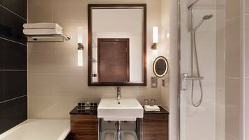 A modern bathroom with a white sink, dark wooden vanity, a glass-enclosed shower, and a large mirror.