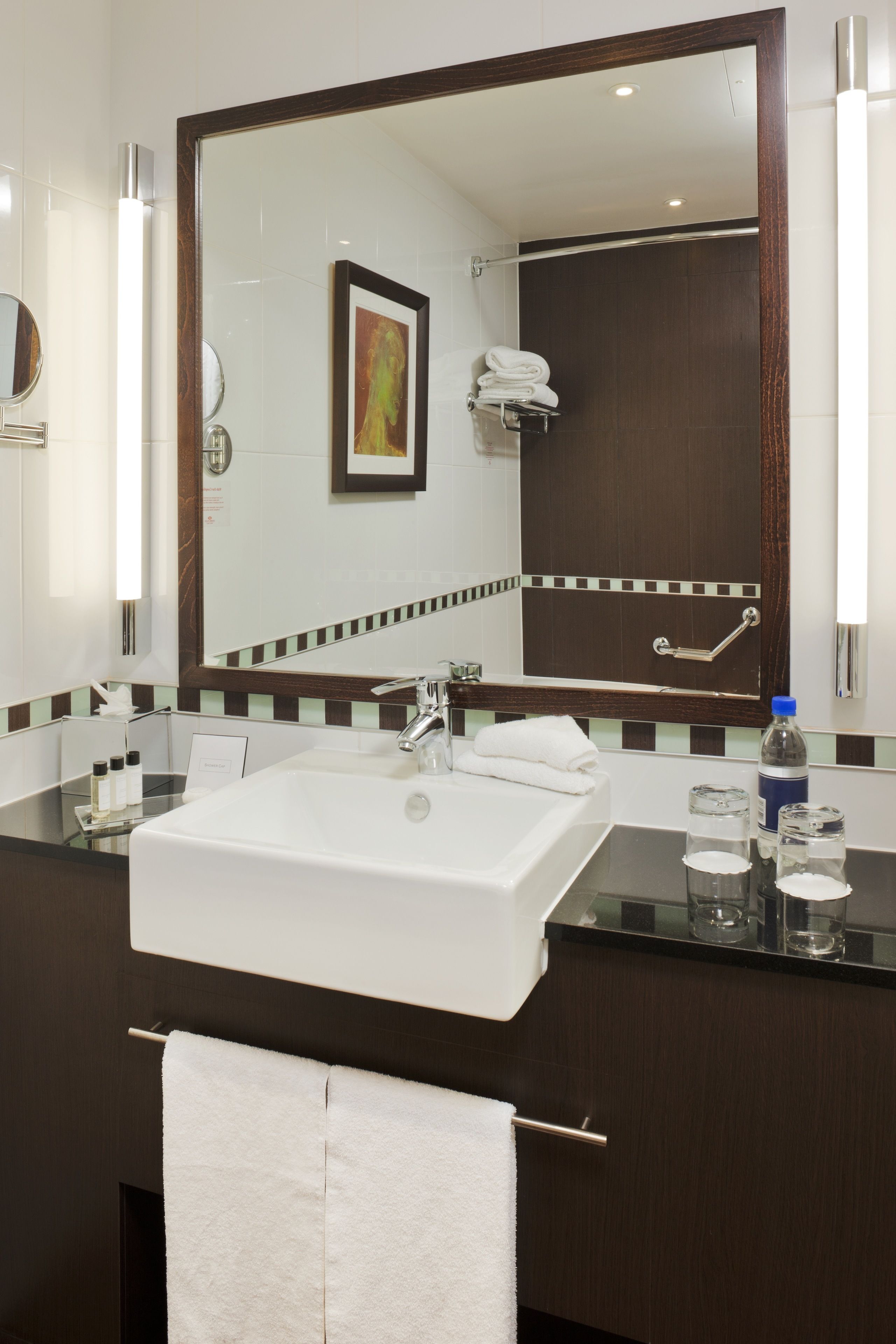 A modern bathroom with a large mirror, a white sink, and a glass countertop.