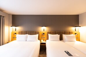 A hotel room with two beds, each with white linens and pillows, a wooden headboard, and a nightstand with a lamp and phone. - Crowne Plaza London- Gatwick Airport by IHG (Crawley)