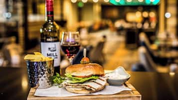 Un repas composé d’un hamburger, de frites et d’une boisson, le tout servi sur une planche en bois.