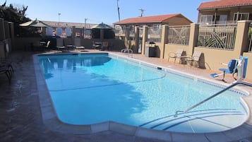 Una piscina rectangular con un solárium empinado, rodeada de sillones de descanso y un área de estar cubierta.