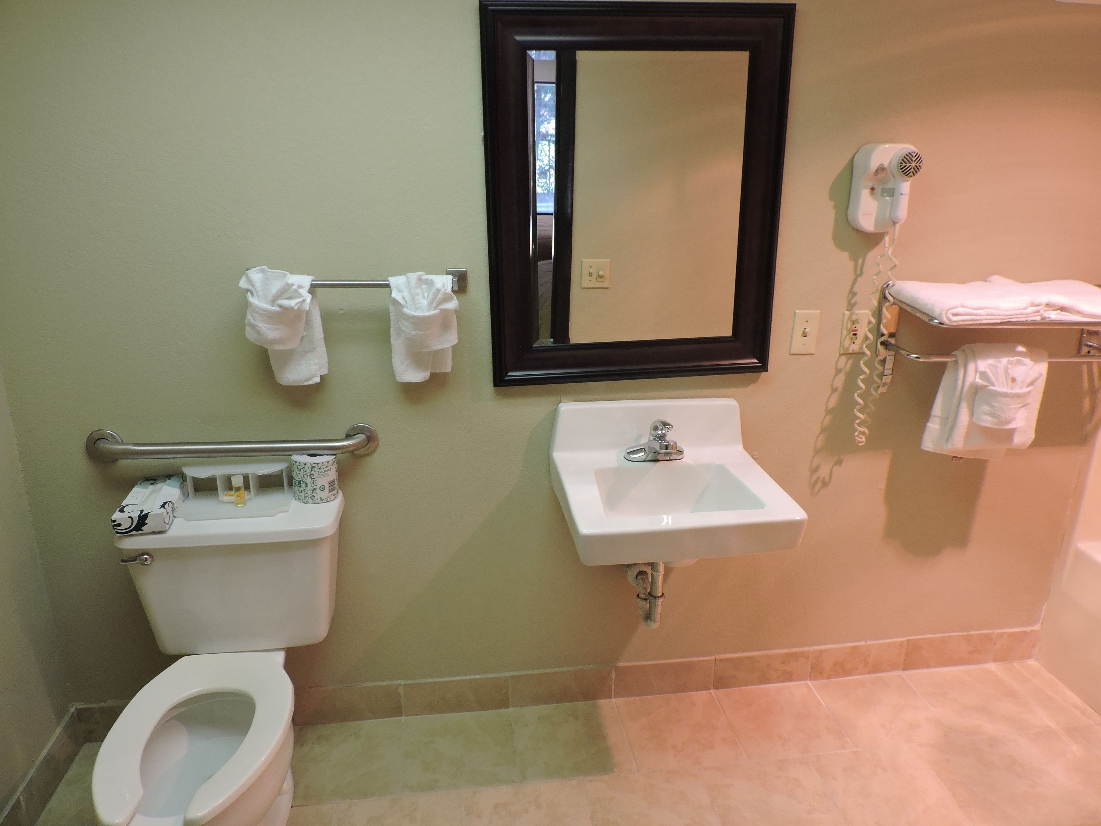 A bathroom with a toilet, sink, and hand dryer.