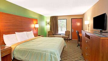 Une chambre d’hôtel avec un grand lit, un bureau avec une chaise, une télévision et une armoire.