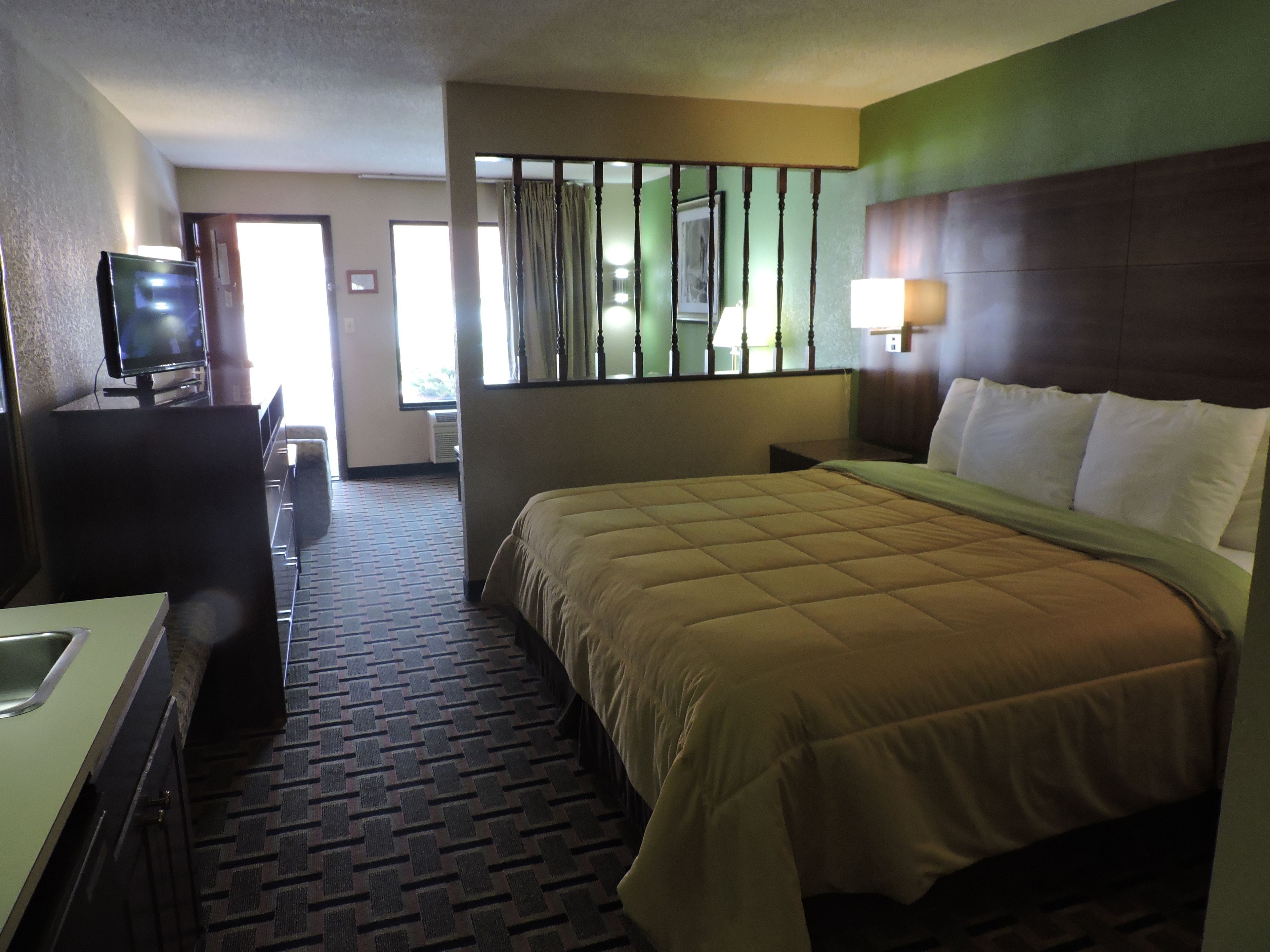 Une chambre d’hôtel avec un lit, une télévision, un bureau et une salle de bain.