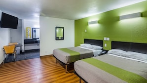 Una habitación de hotel con dos camas, un pequeño comedor y un televisor.
