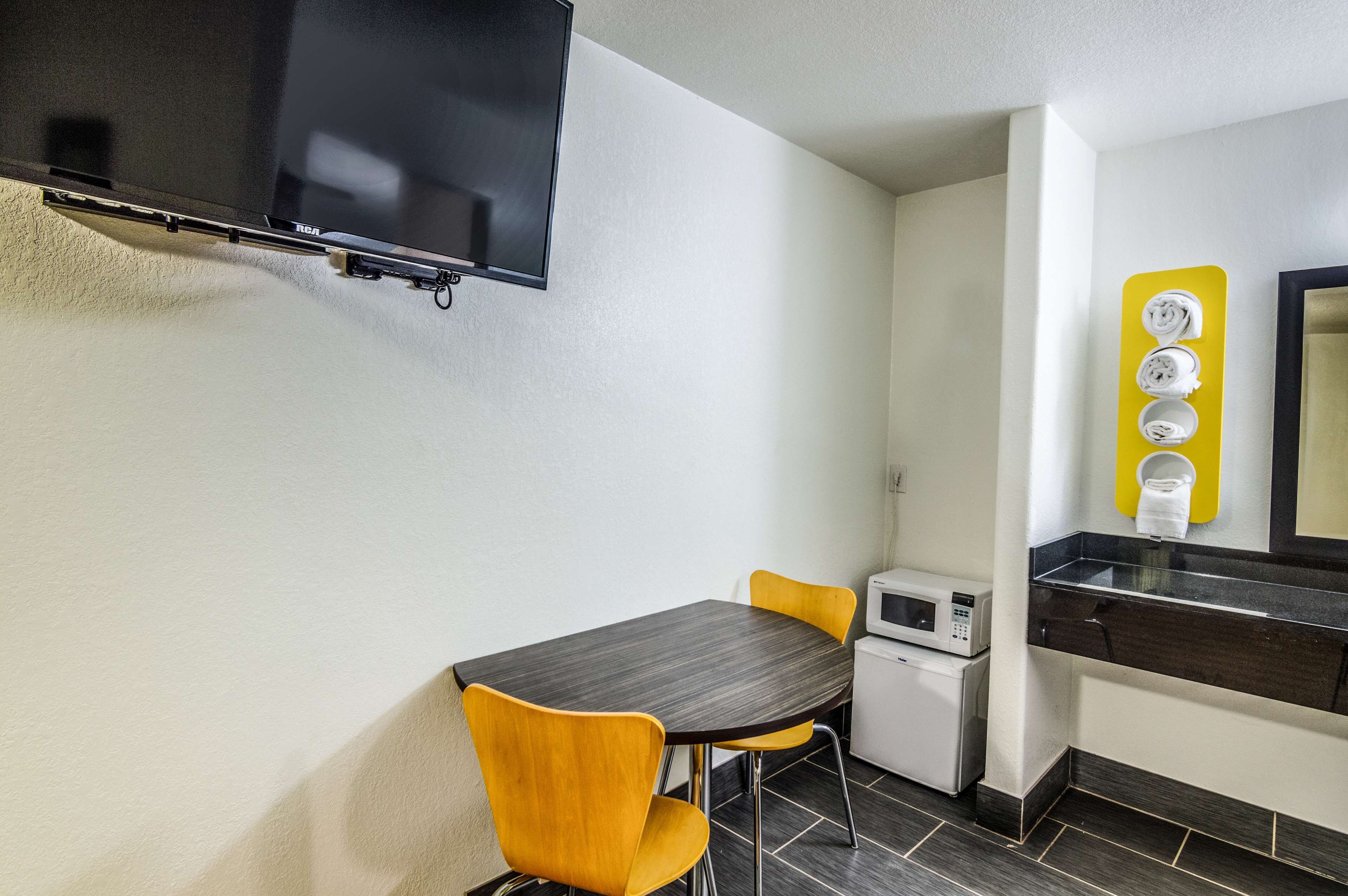 A compact kitchenette with a microwave, a small refrigerator, and a yellow towel rack.