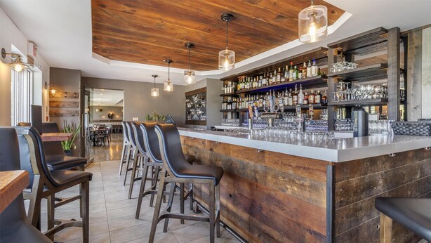 A bar area with wooden accents, bar stools, and a well-stocked liquor shelf. - Best Western Plus Chocolate Lake Hotel (Halifax)