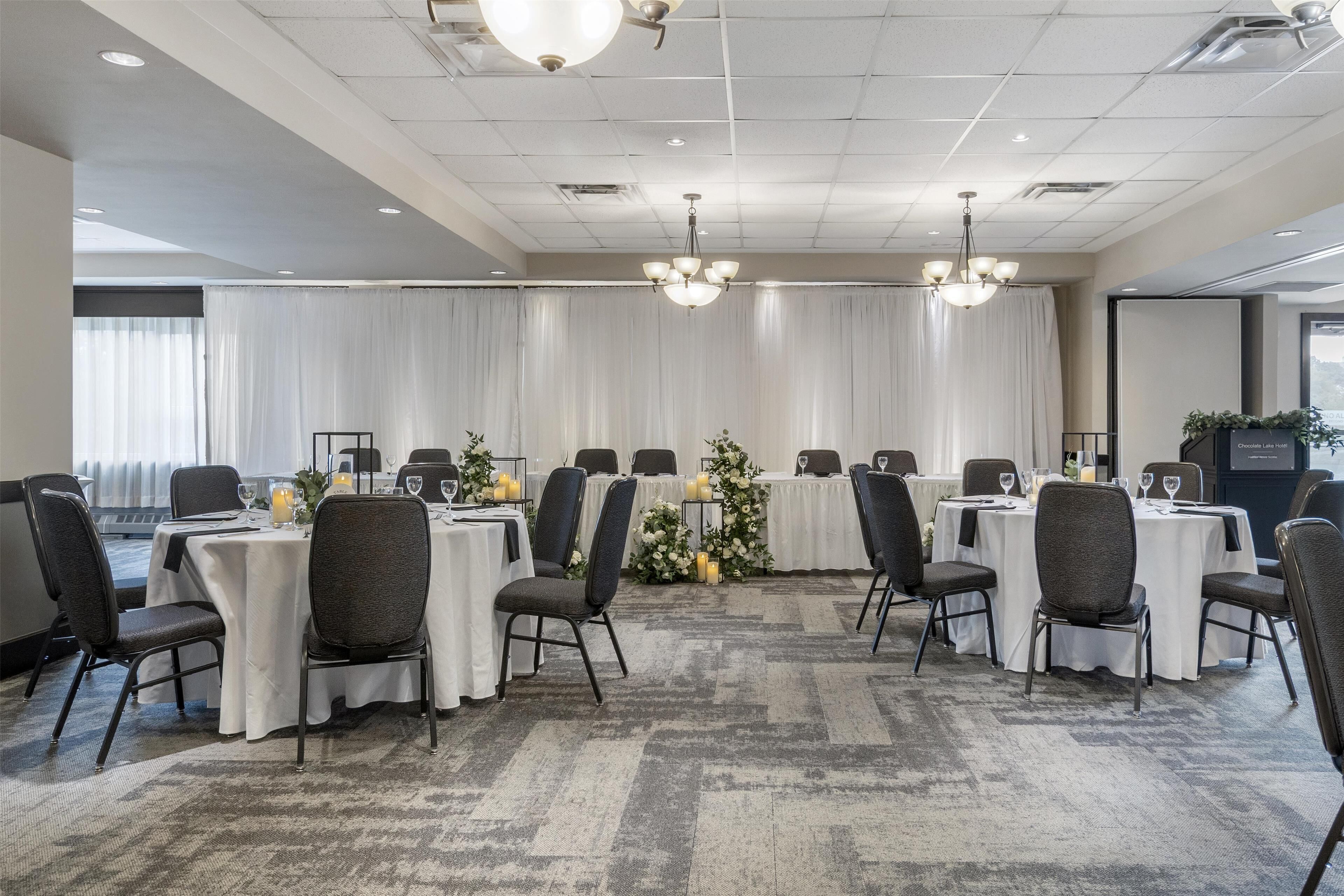 A conference room with round tables, chairs, and a chandelier.