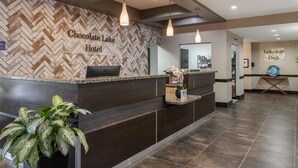 A hotel reception area with a herringbone patterned wall, a reception desk, and a potted plant. - Best Western Plus Chocolate Lake Hotel (Halifax)