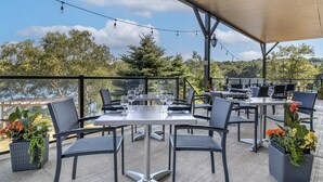An outdoor patio with tables and chairs, potted plants, and a view of trees and hills. - Best Western Plus Chocolate Lake Hotel (Halifax)