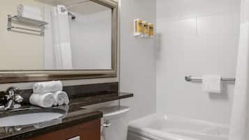 A bathroom with a sink, mirror, toilet, and bathtub.
