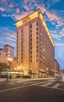 Un hotel grande de varios pisos, con una entrada destacada y una serie de balcones.