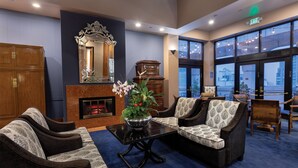 A lobby with a fireplace, seating area, and large windows offering a view. - The Donatello (San Francisco)