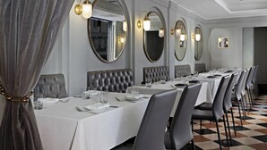 A formal dining room with long tables, leather chairs, and wall-mounted mirrors. - The Donatello (San Francisco)