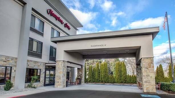 A hotel entrance with a stone facade, a clear sky, and a parking area with handicapped accessibility.