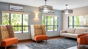 A spacious room with large windows, a sofa, two armchairs, and a patterned rug.