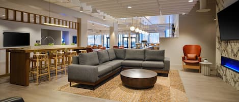 A modern living room with a sectional sofa, a round coffee table, and a TV mounted on the wall.