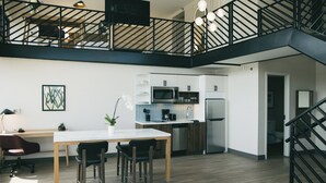 Une cuisine moderne avec un coin repas, un plancher en bois et un escalier noir.