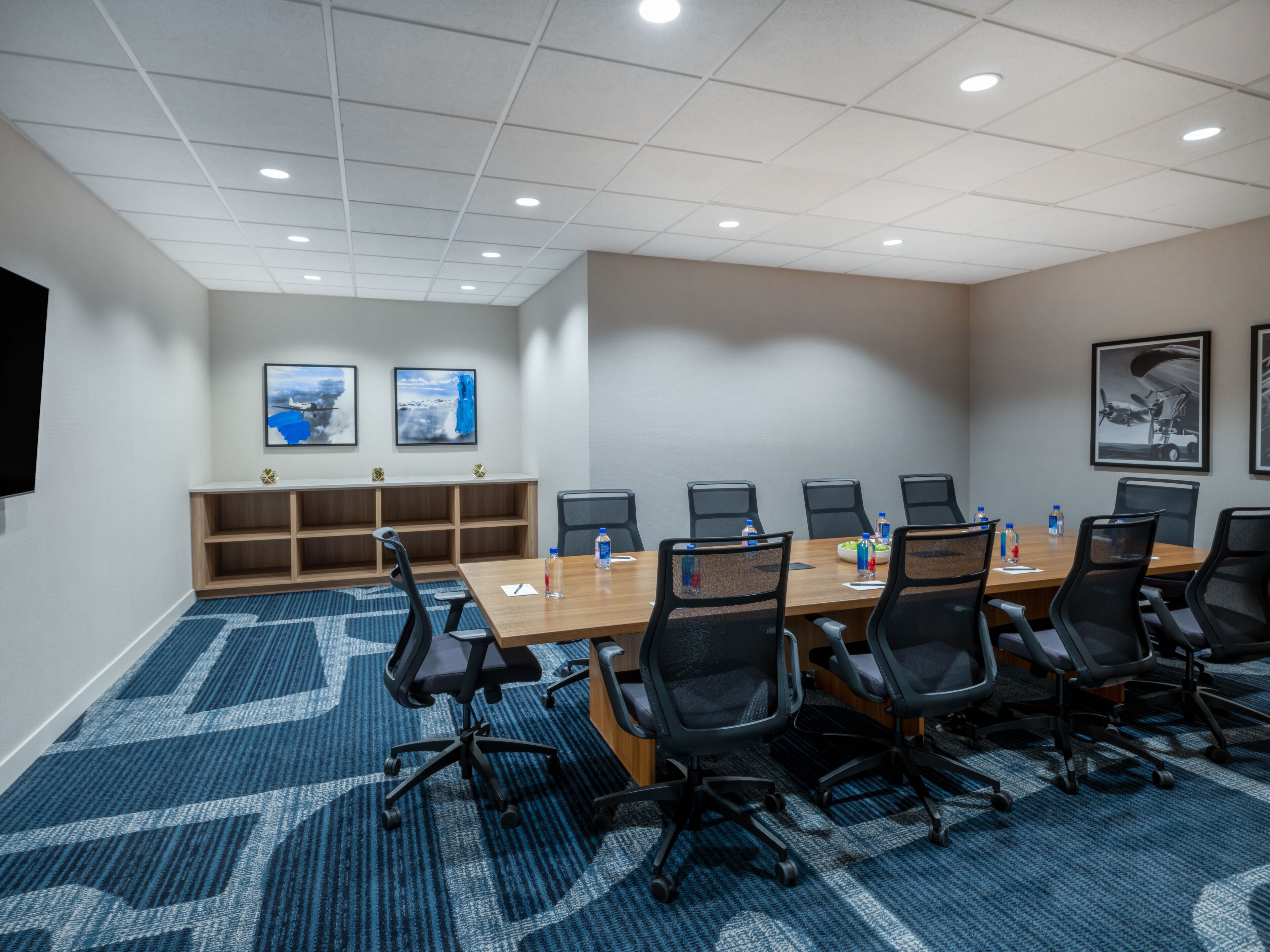 A conference room with a long table, black chairs, and a blue carpet.