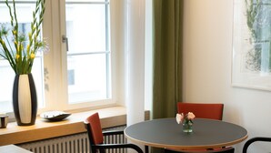 A modern dining area with a round table, red chairs, a vase with flowers, and a window with curtains. - Boutique Hotel Helmhaus Zurich (Zürich)