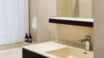 A modern bathroom with a large mirror, a bathtub, and a sink.