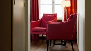 A room with two red chairs, a floor lamp, and a window with red curtains. - Boutique Hotel Helmhaus Zurich (Zürich)