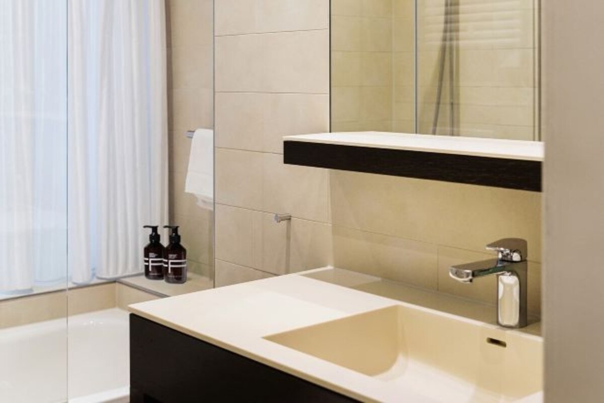 A modern bathroom with a white sink, a mirror, and a shower.