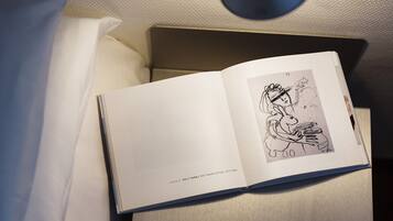A book open on a bedside table with a lamp above it.