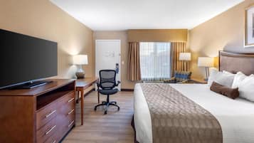 A hotel room with a bed, a desk with a chair, a television, and two lamps.