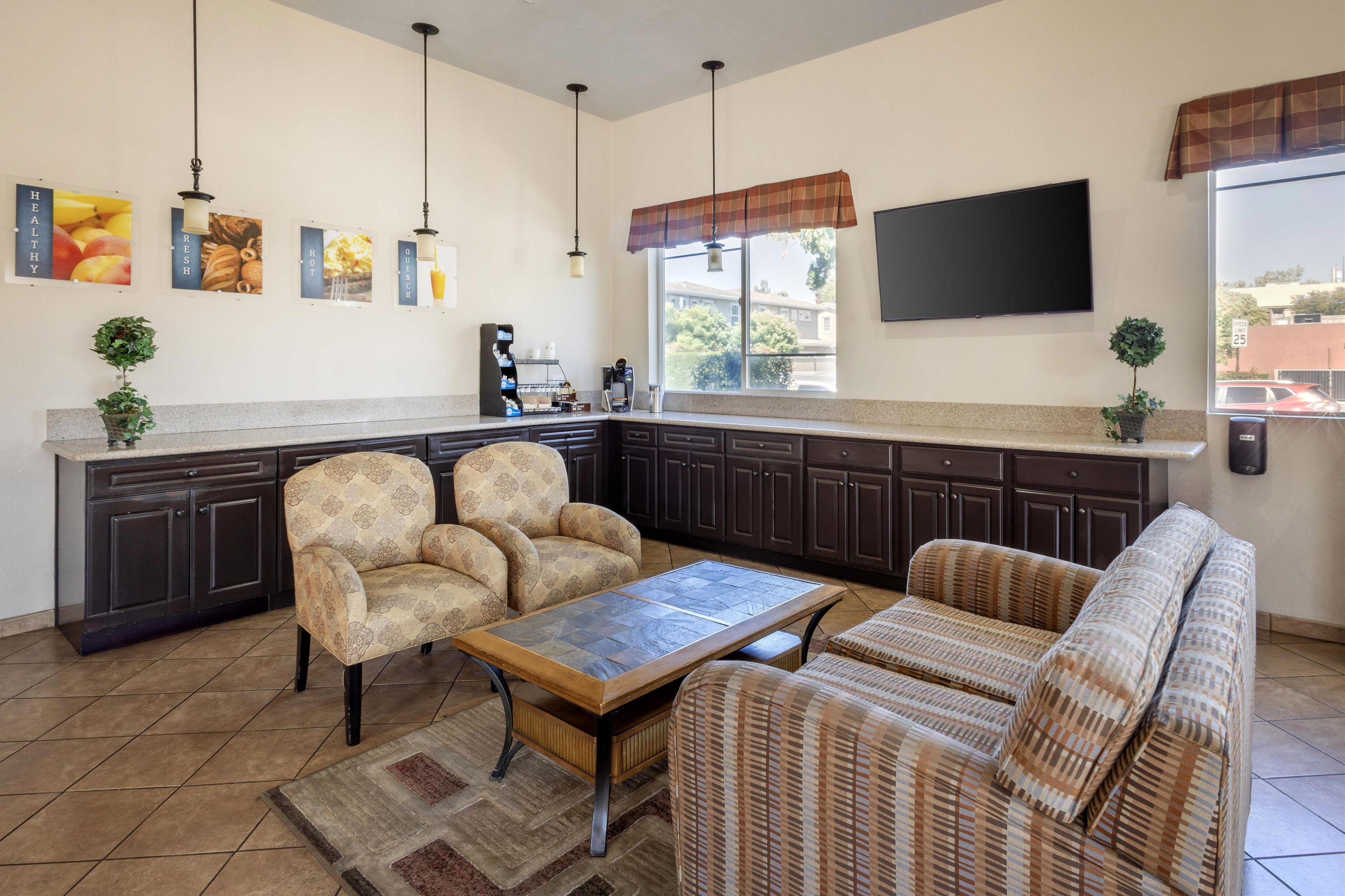 A modern kitchen with dark cabinets, a coffee station, and a seating area with patterned sofas and chairs.