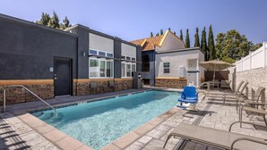 Ein Swimmingpool mit klarem, blauem Wasser, umgeben von Liegestühlen und einer überdachten Sitzgelegenheit.