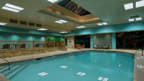 Une piscine intérieure à l’eau claire, dotée d’une terrasse en bois et d’un plafond agrémenté de lucarnes.