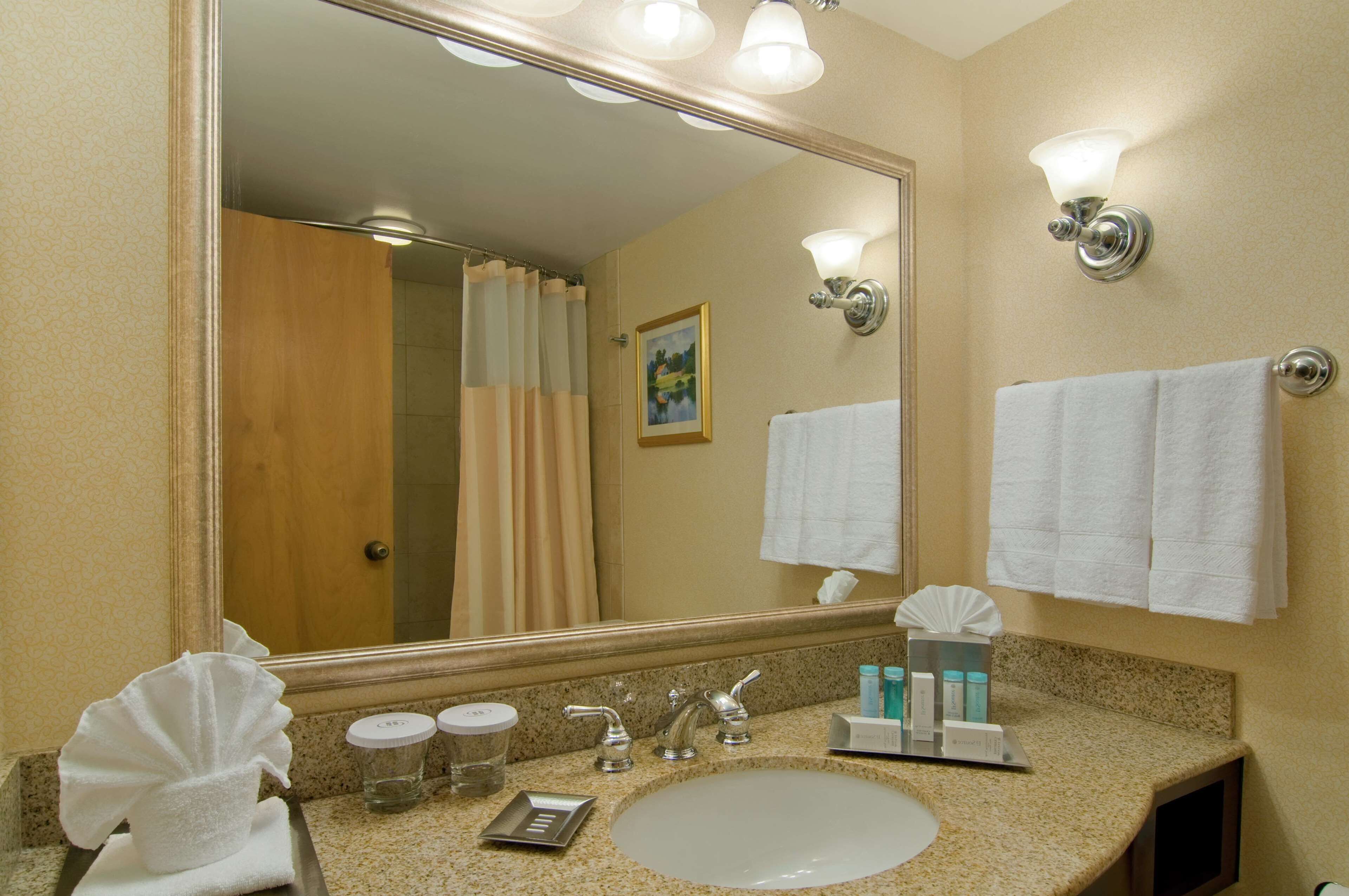 A bathroom with a sink, mirror, and towel rack.