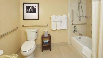 Un bagno con servizi igienici, bidet e vasca da bagno. Sono presenti maniglie di sostegno, un portasciugamani e un quadro appeso al muro.