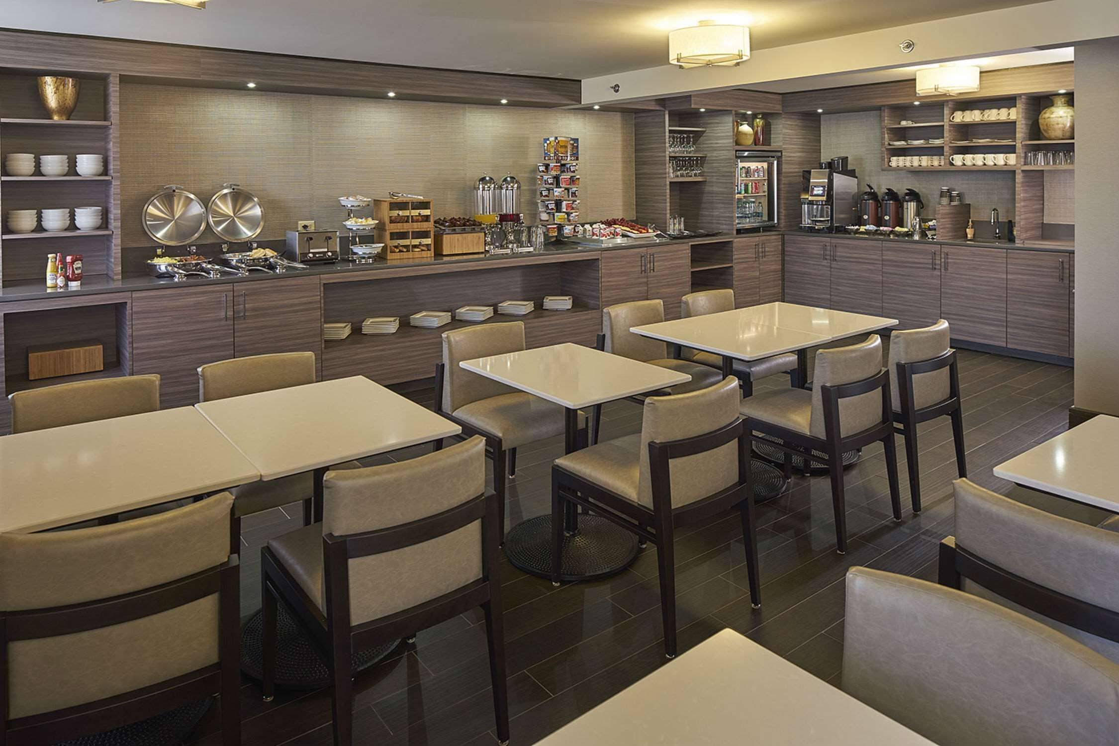 Un restaurant moderne doté de nombreuses tables et chaises, d’un espace buffet proposant une variété de plats et d’un coin café.