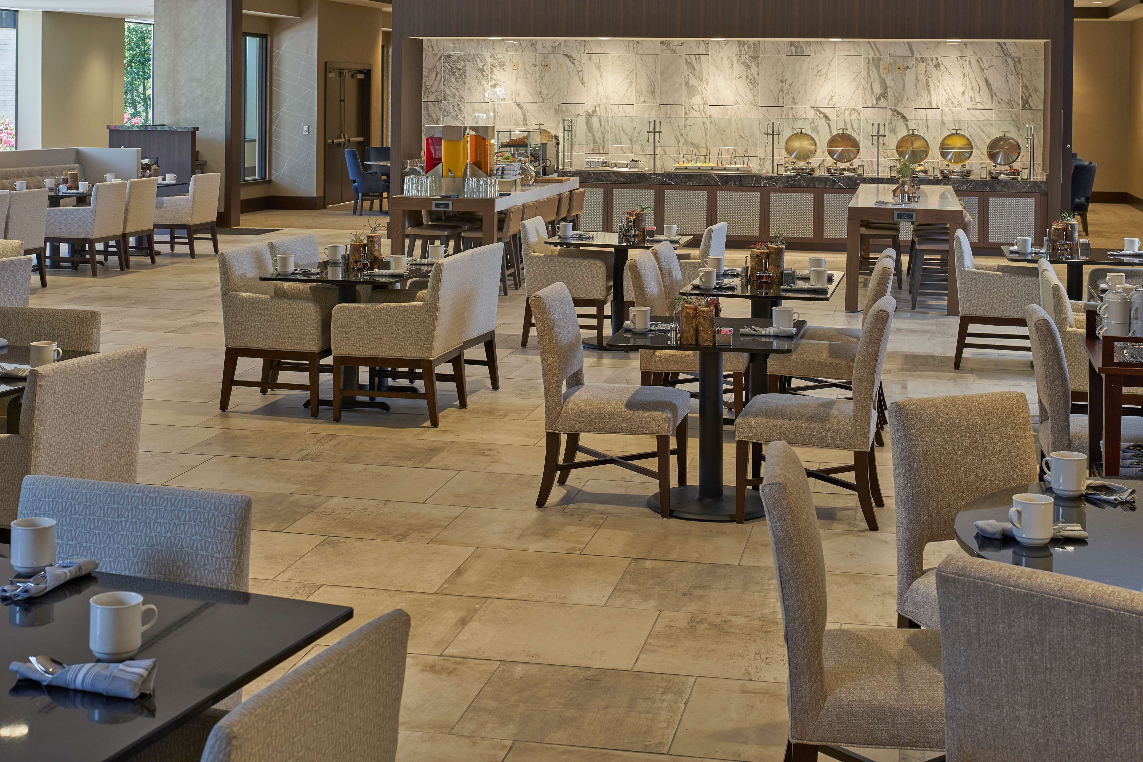 A spacious hotel lobby with multiple seating areas, a marble reception desk, and a well-lit interior.