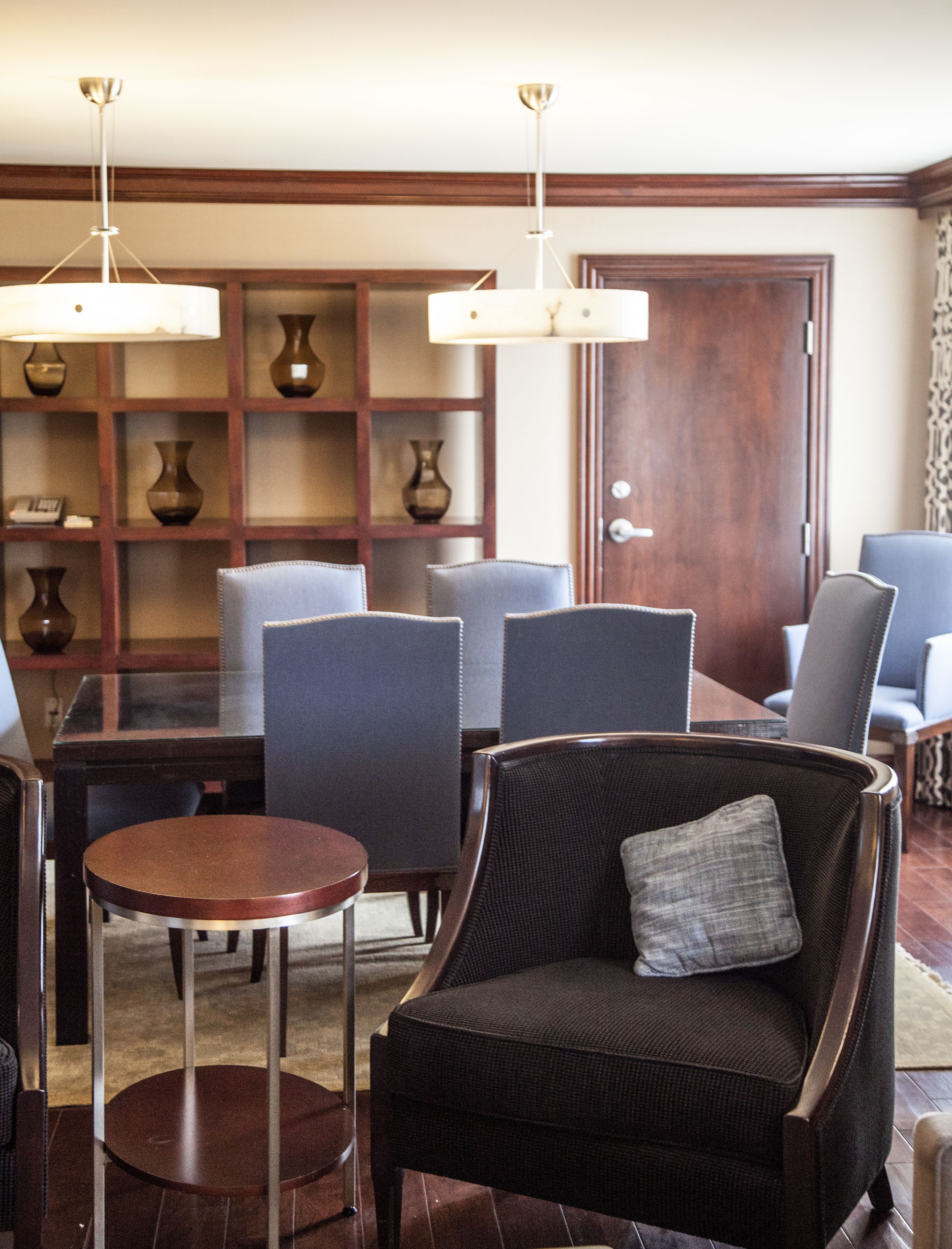 A dining area with a wooden table, chairs, and a bookshelf with vases.