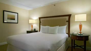Habitación de hotel con una cama grande, dos lámparas de noche, un cuadro en la pared y una mesita con un teléfono y una lámpara.