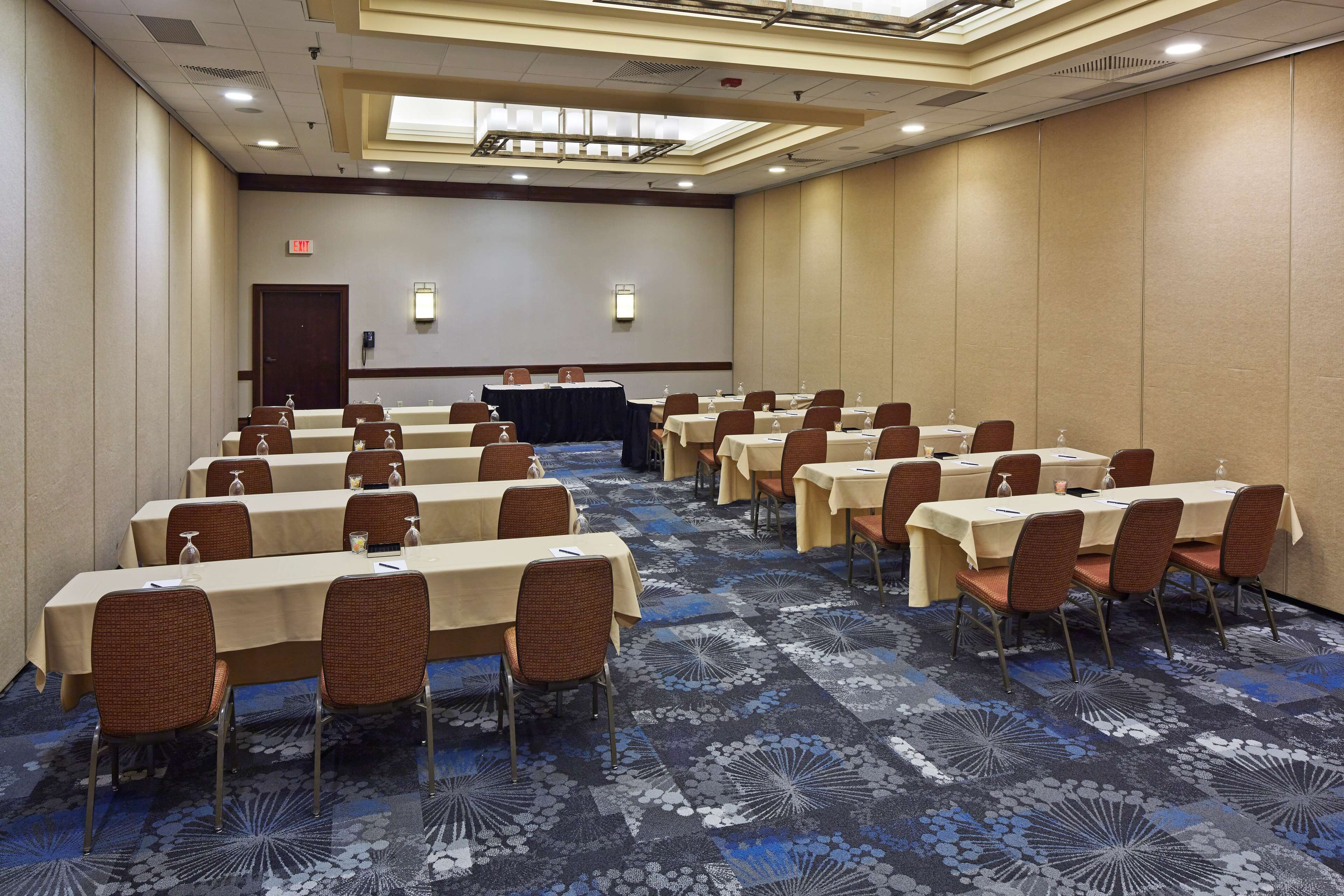 Une salle de conférence dotée de plusieurs tables et chaises, ainsi que de bouteilles d’eau et de porte-noms.