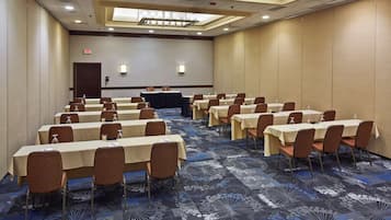 Une salle de conférence dotée de plusieurs tables et chaises, ainsi que de bouteilles d’eau et de porte-noms.