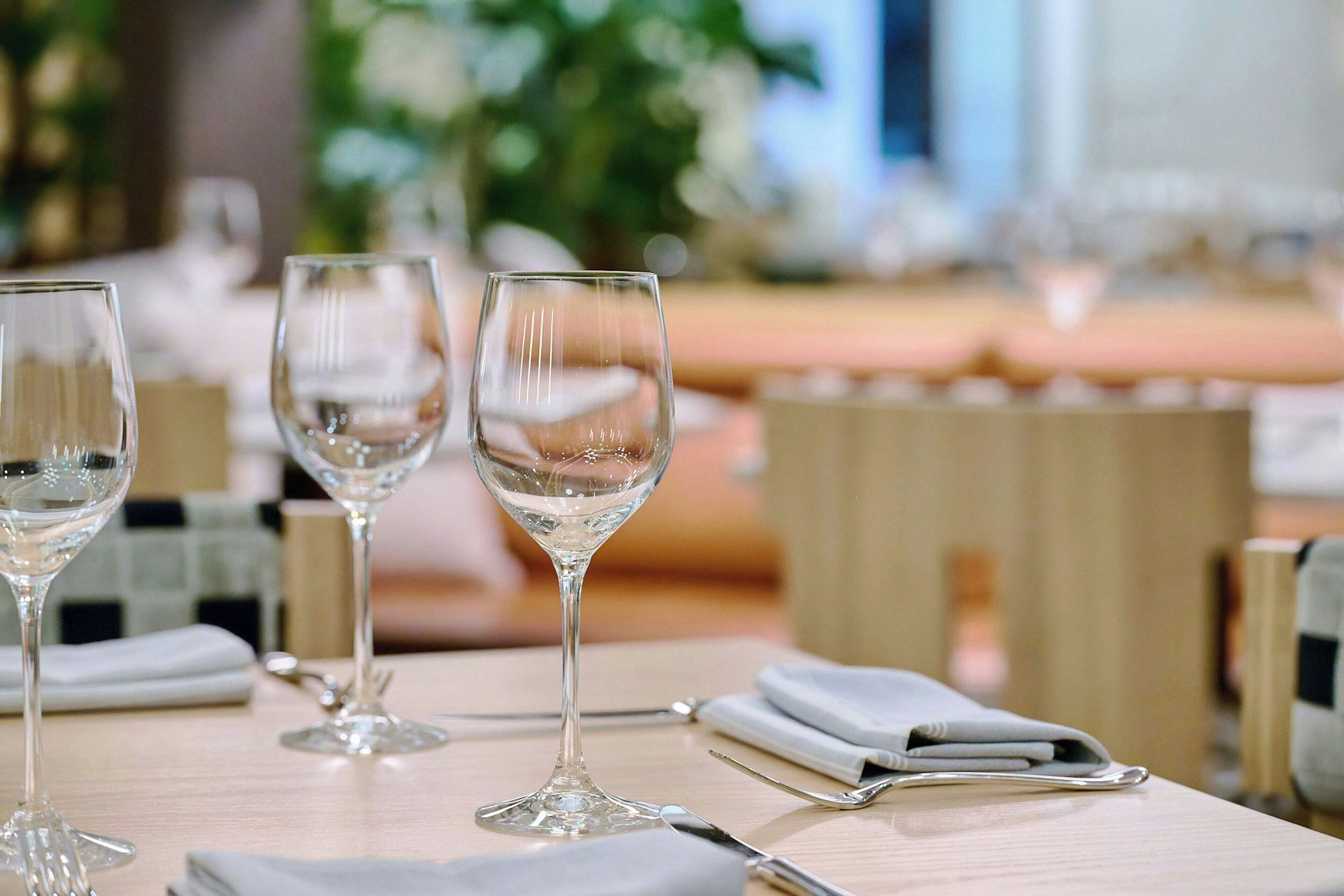 Une table mise pour le dîner, avec trois verres à vin et une serviette pliée.