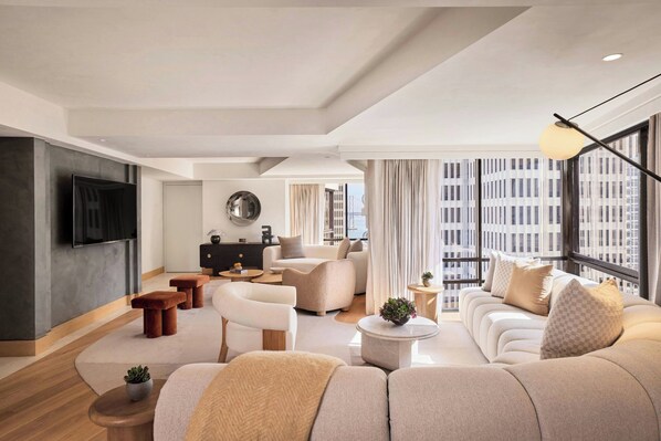 Relax in a spacious living room with a large sofa set, flat-screen TV, and city views.