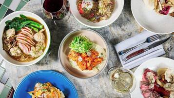 Forskellige retter på et bord, herunder en skål suppe, en tallerken med kød og grøntsager, og en blå tallerken med en anden ret.