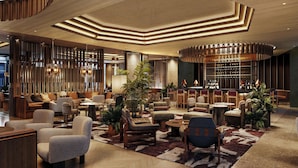 A modern lobby with a mix of seating areas, a bar, and a large plant. - The Jay, Autograph Collection (San Francisco)