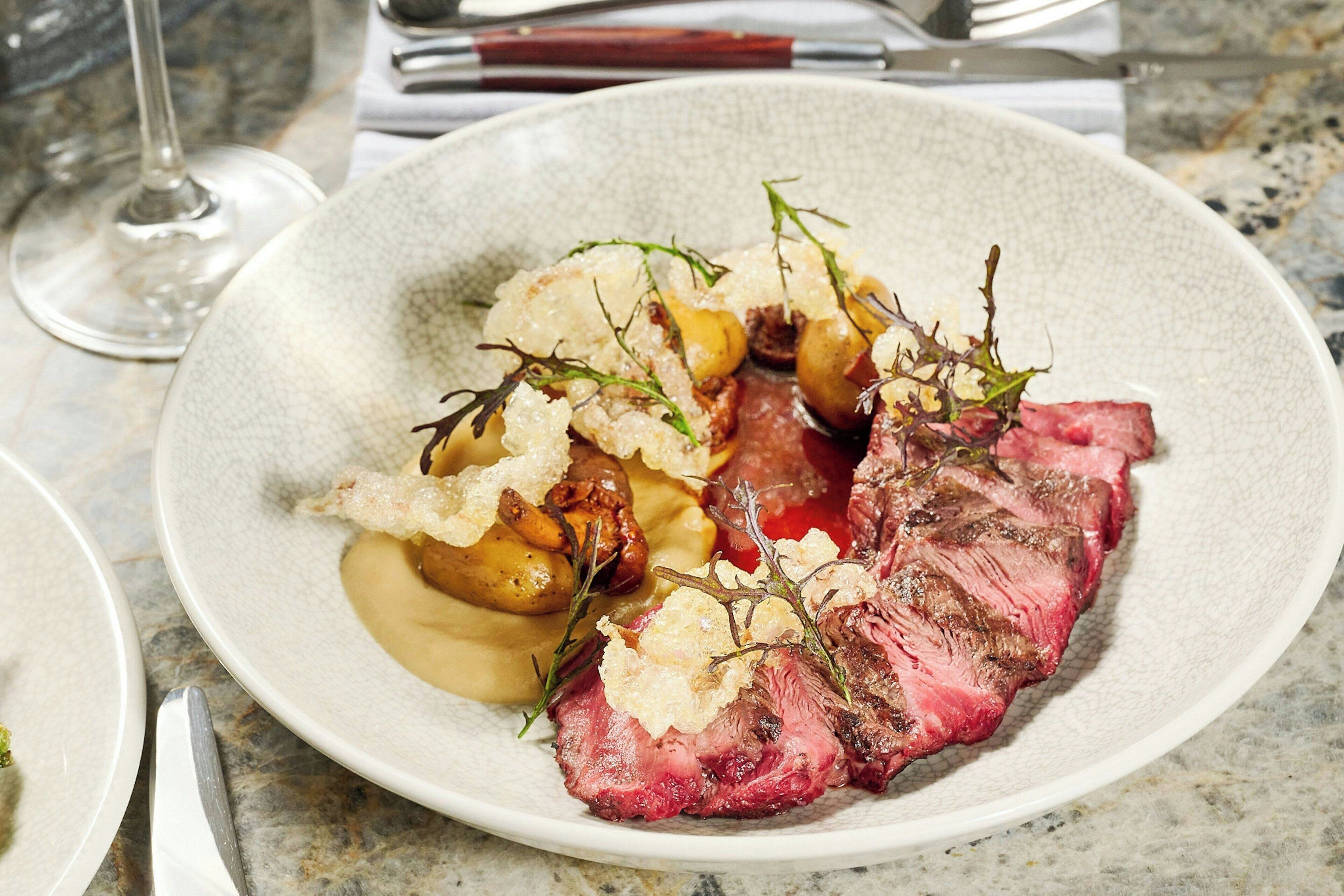 A plate of food with steak, potatoes, and a creamy sauce.